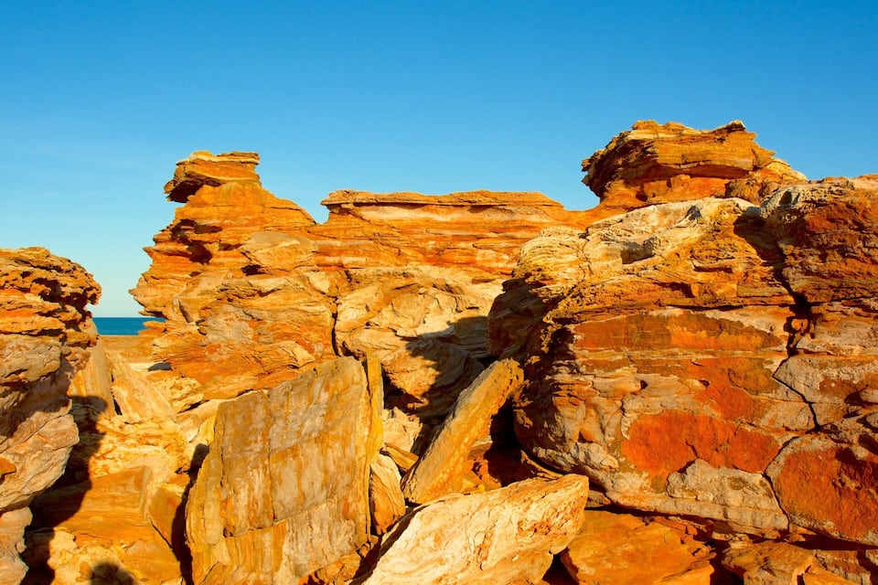 A rocky landscape with layered sedimentary formations and a clear blue sky.