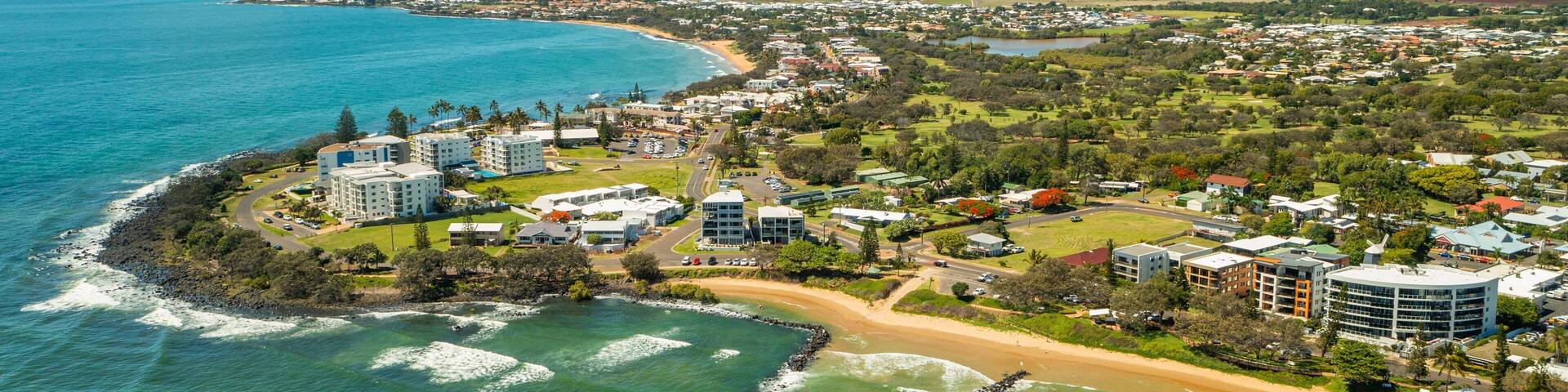A coastal town with a beach, ocean, and residential buildings.