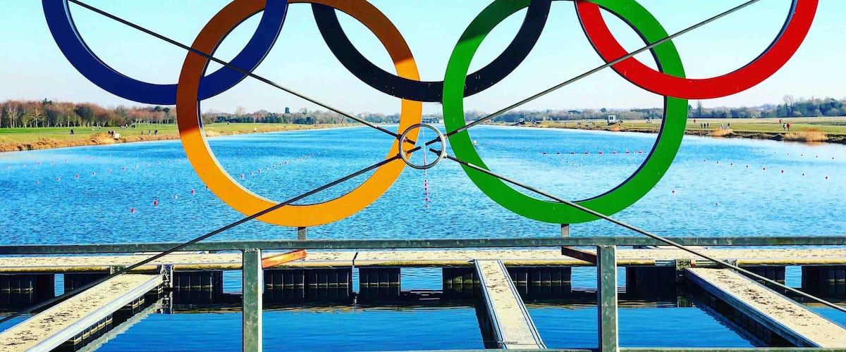 Olympic rings over a river with a bridge in the foreground.
