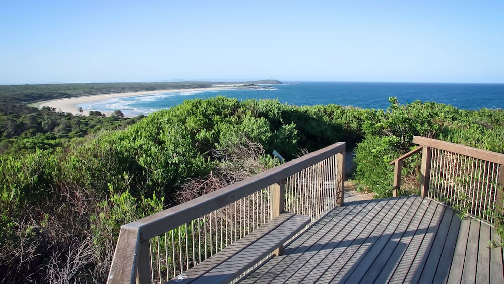 Eine Holzterrasse mit Blick auf einen Strand und den Ozean.