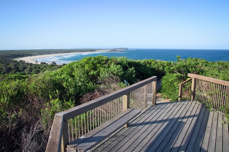 A wooden deck overlooking a beach with ocean views.