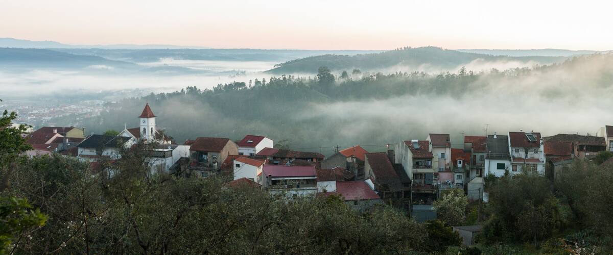 A town nestled in a valley with mist-covered hills in the background.
