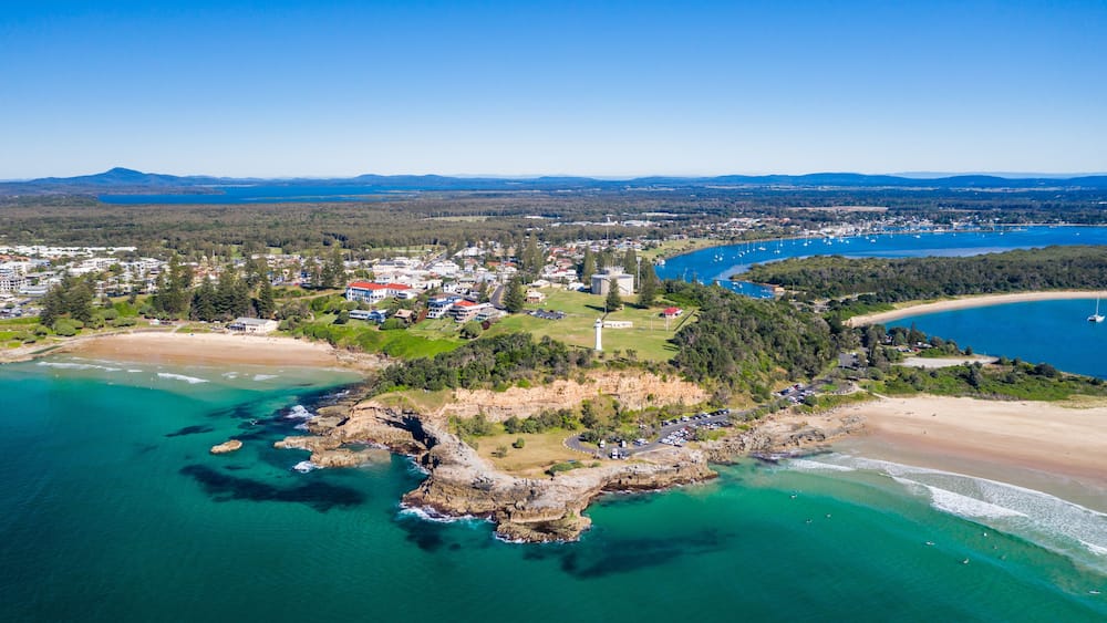 Une ville côtière dotée d’un phare, d’une plage et d’eaux d’un bleu limpide.