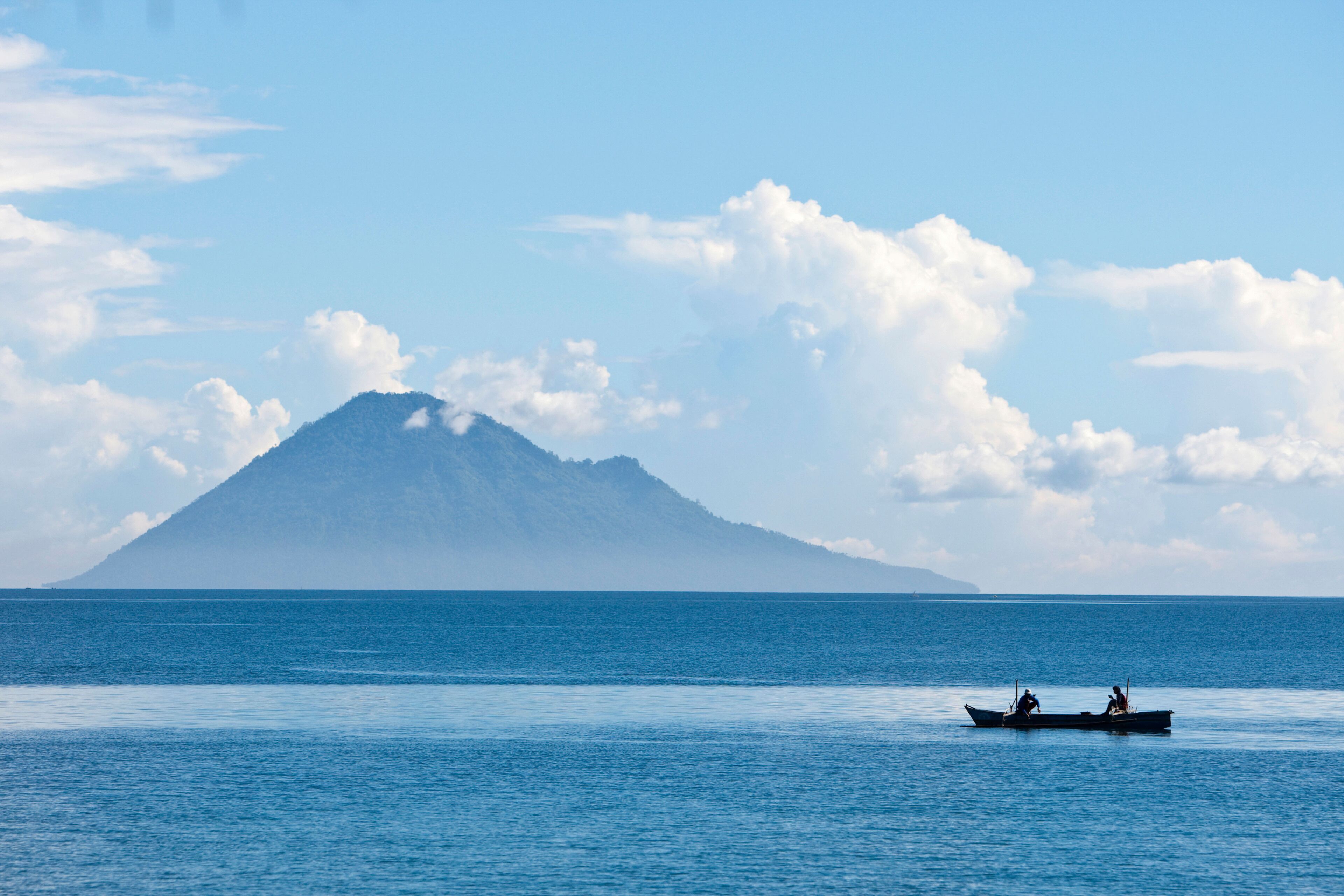 A calm sea with a boat and a mountain in the distance.