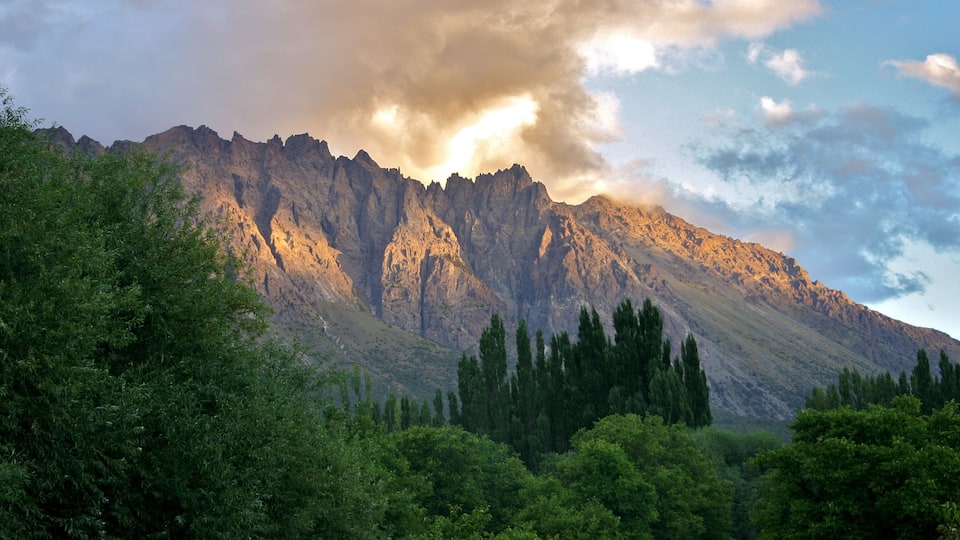 A mountain range with dense green forests in the foreground and a clear sky.