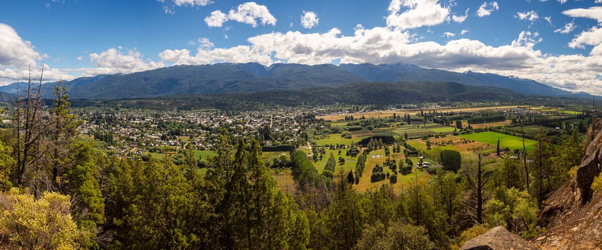 A town nestled in a valley with mountains in the background.