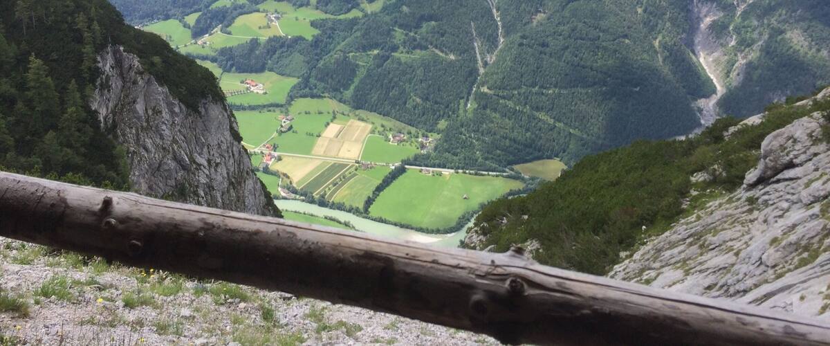 A mountainous landscape with green valleys, fields, and a winding road.