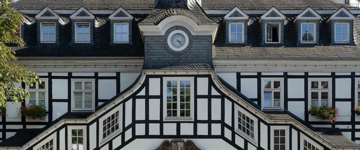 A historic building with a clock tower, black and white timber framing, and a green door.