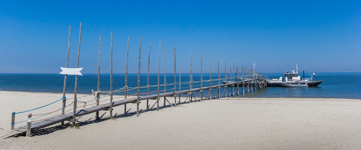 Panorama of a jetty and ferry in the blue water of the Wadden sea, The Netherlands