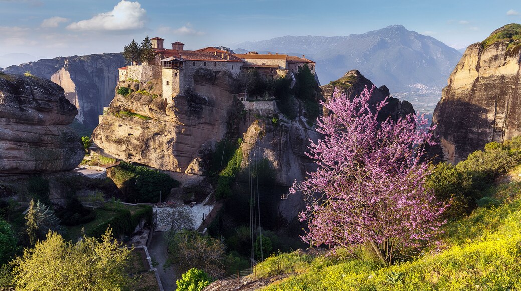 Scenic image of spring Landscape Monastery Meteora Greece. Stunning spring panoramic landscape. View at mountains and blossoming trees during sunrise. Wonderful nature scene.