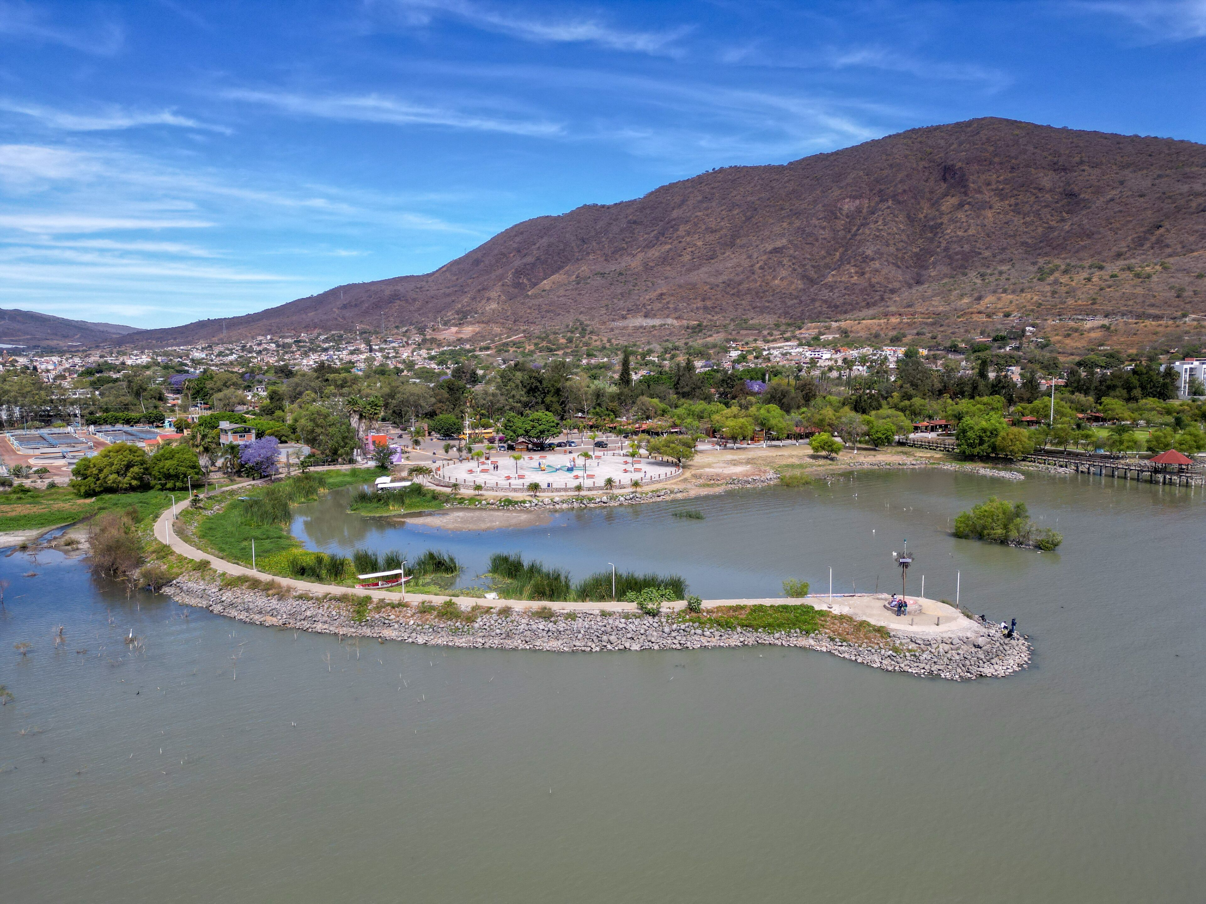 Elevated aerial shot of Jocotepec Pier along Lake Chapala with mountains in the background in Jalisco Mexico