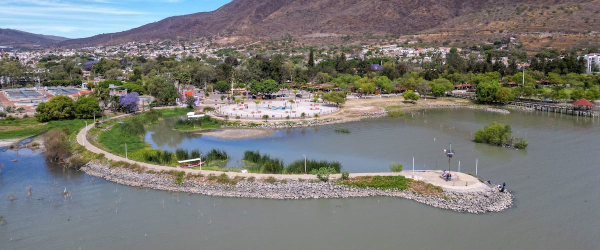 Une rivière bordée d’un parc, avec une montagne en arrière-plan.