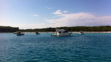 A calm sea with several boats anchored near a beach.