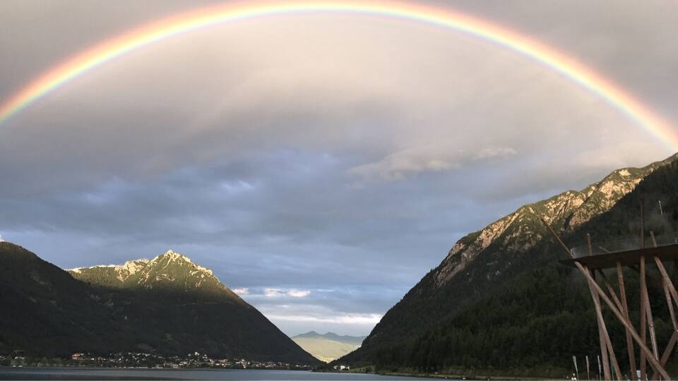 A mountain landscape with a rainbow arching over a valley.