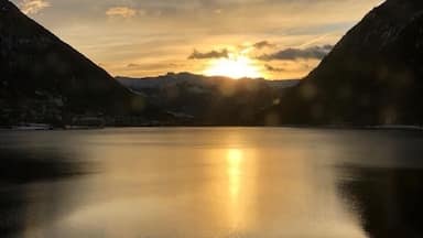 A calm lake with mountains on either side and the sun setting in the background.