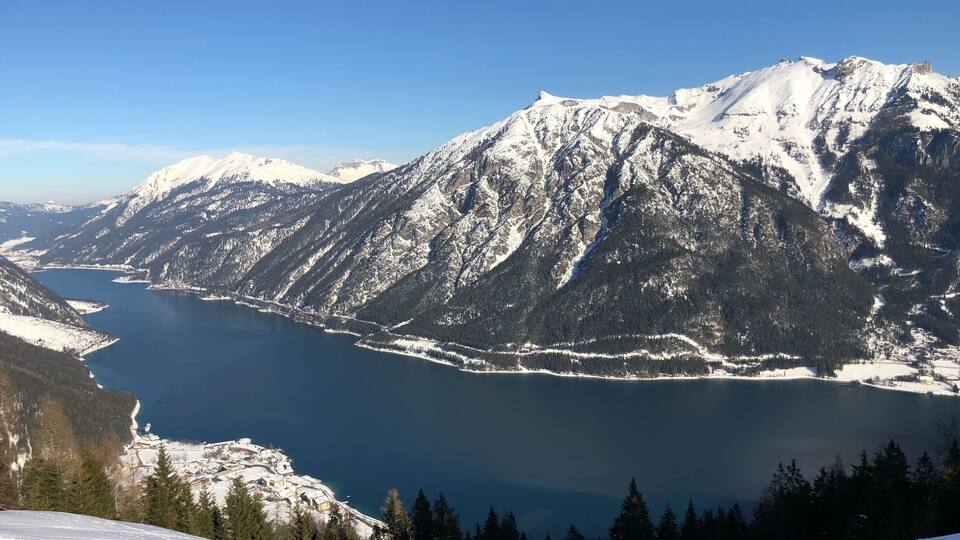 A snow-covered mountain range with a lake at its base.