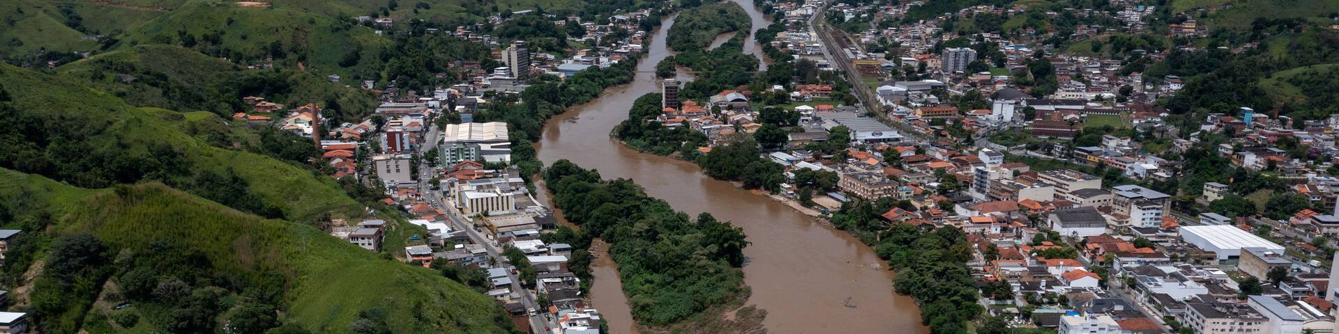 A river winding through a town surrounded by green hills.