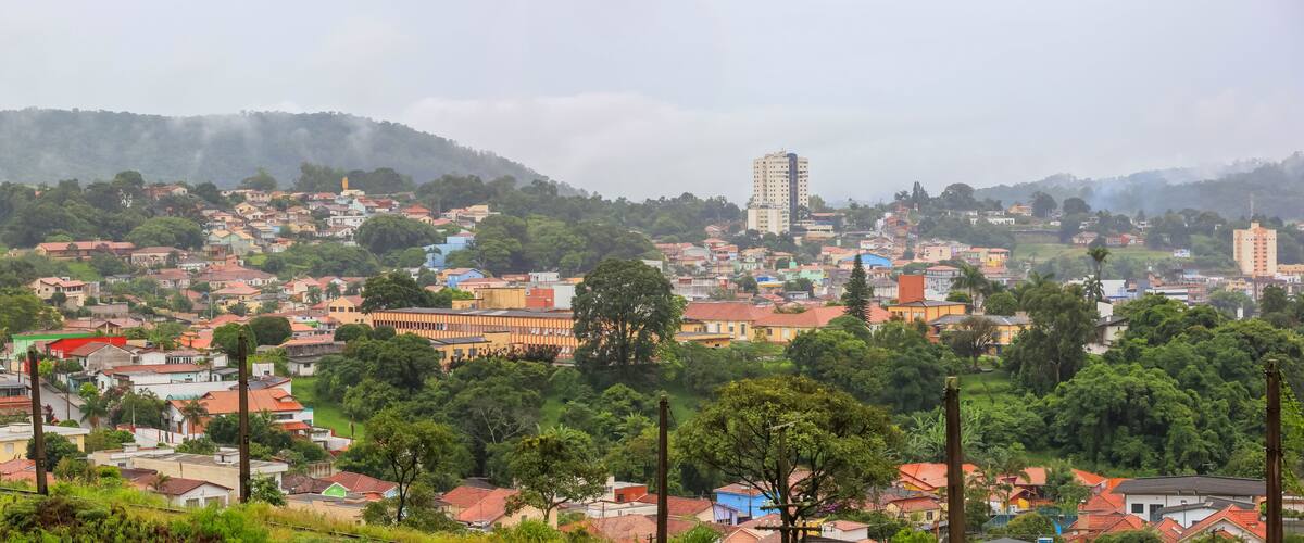 A town with colorful buildings, a prominent church, and a hill in the background.