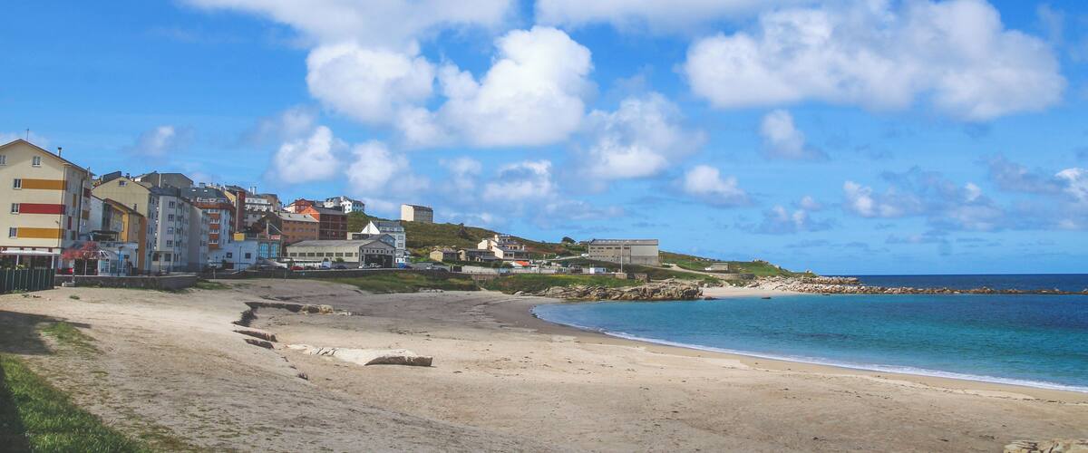 A beach with buildings in the background and a clear blue sky.