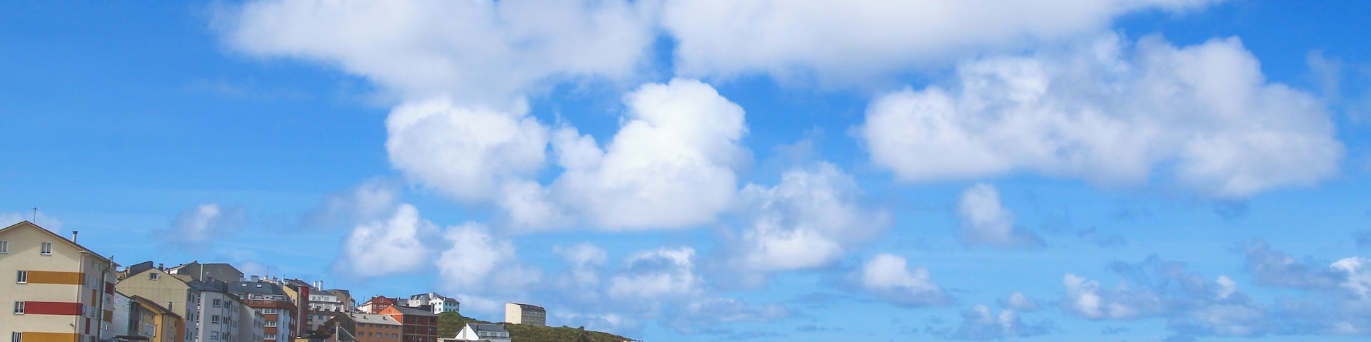 A beach with buildings in the background and a clear blue sky.