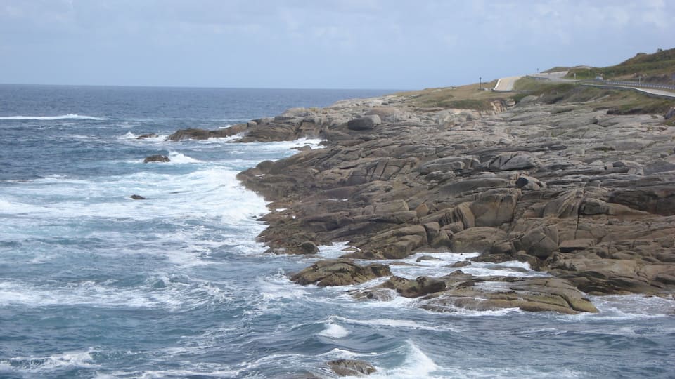 A rocky coastline with waves crashing against the shore.