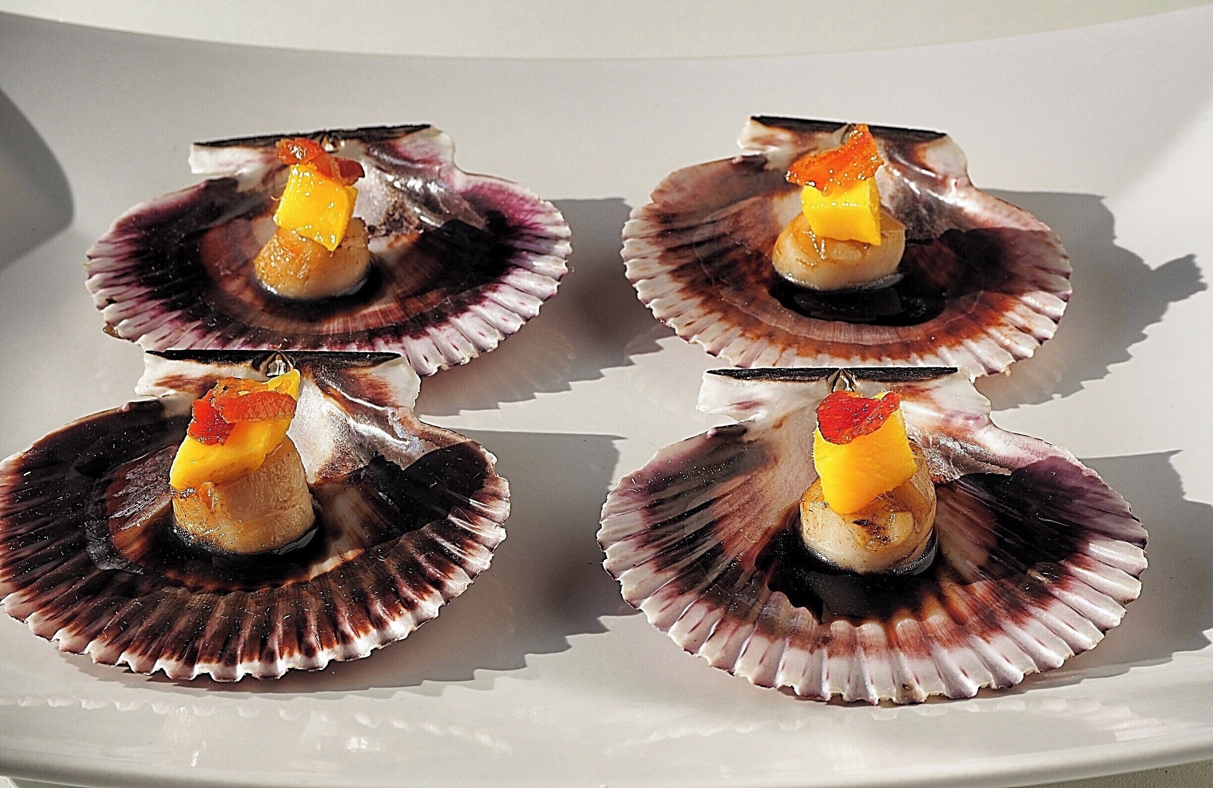 Scallops are characterized by offering two flavors and textures in one shell: the meat, called "scallop", which is firm and white, and the roe, called "coral", which is soft and often brightly coloured reddish-orange. 
In Galician cuisine, scallops are baked with bread crumbs, ham, and onions .Smoked scallops are sometimes served as appetizers or as an ingredient in the preparation of various dishes and appetizers. #Patterns