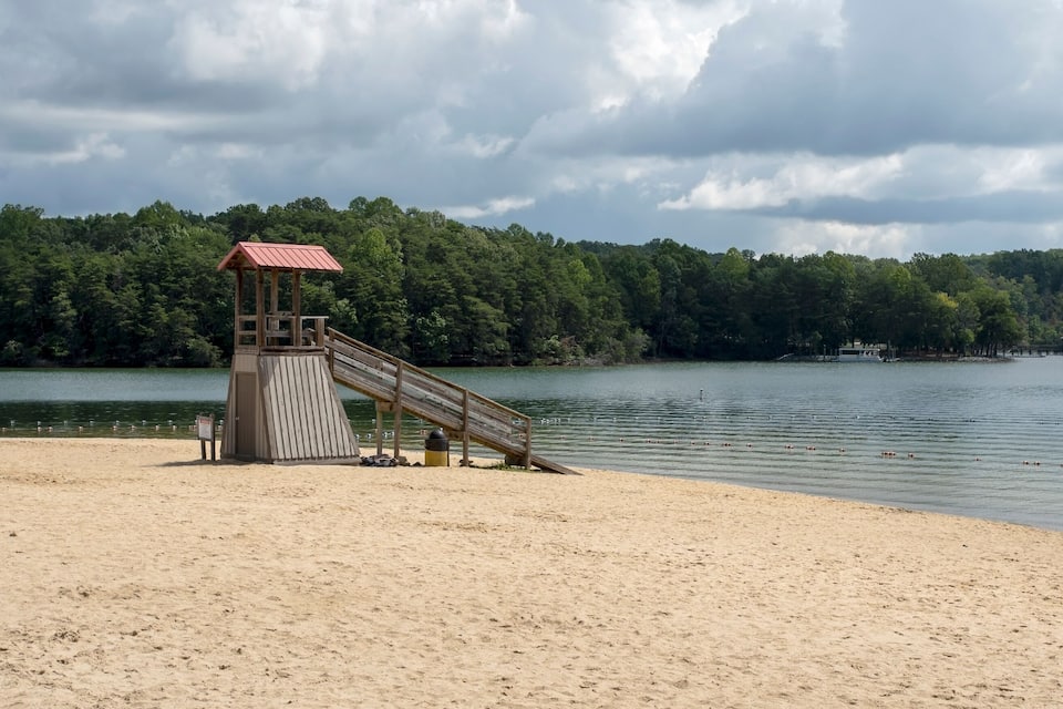 A beach with a lifeguard tower and a wooden slide.