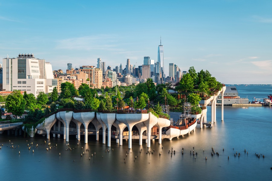 A waterfront cityscape with modern architecture, including a distinctive bridge with arches.