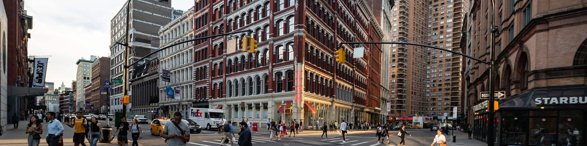 A busy urban street with historic buildings, a Starbucks, and a FedEx truck.