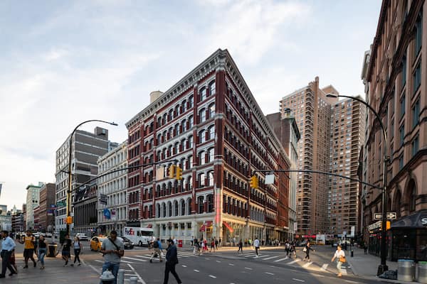 A busy urban street with historic buildings, a Starbucks, and a FedEx truck.