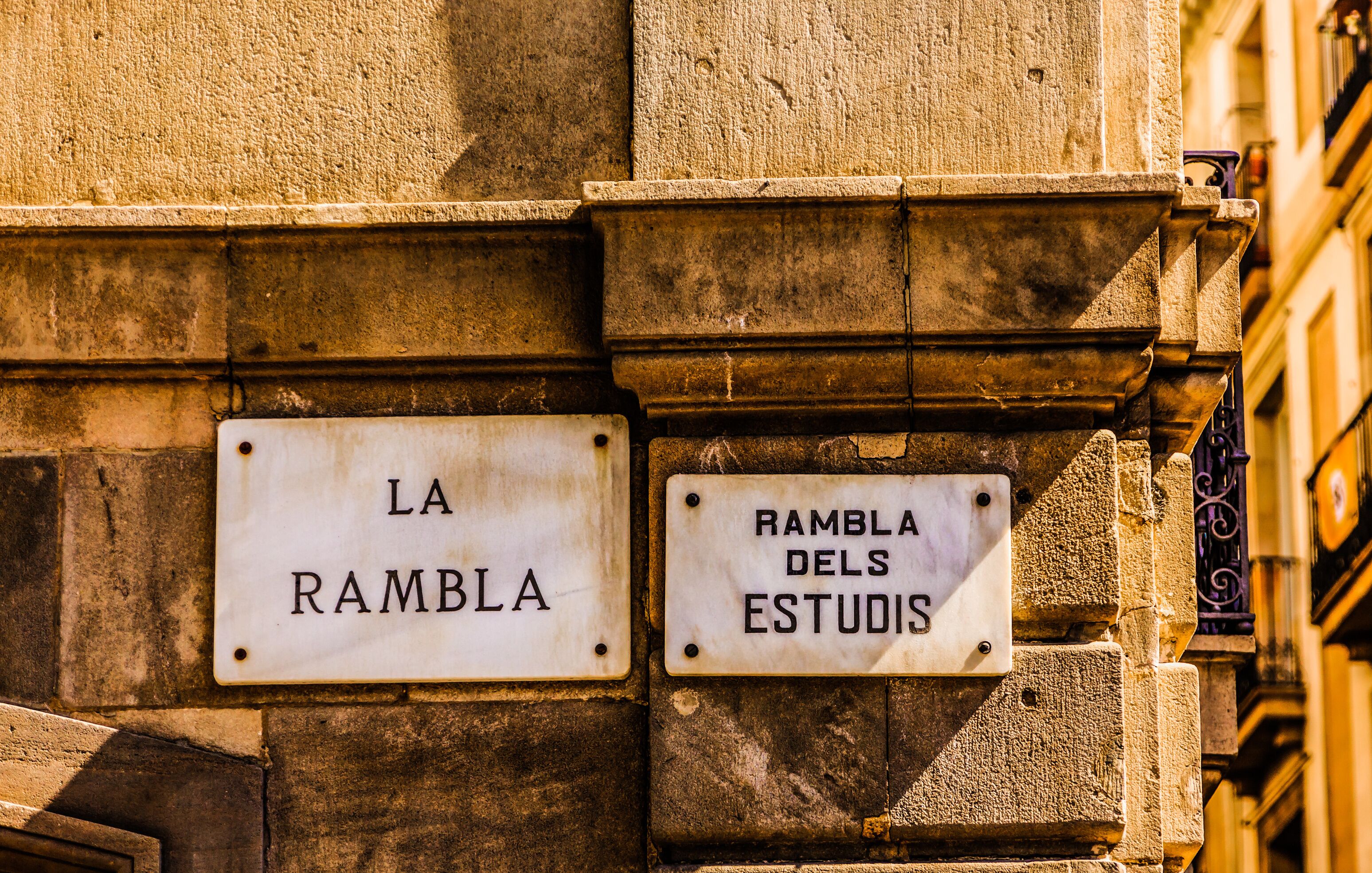 Two street signs on a building wall, one reads "LA RAMBLA" and the other "RAMBLA DELS ESTUDIS".