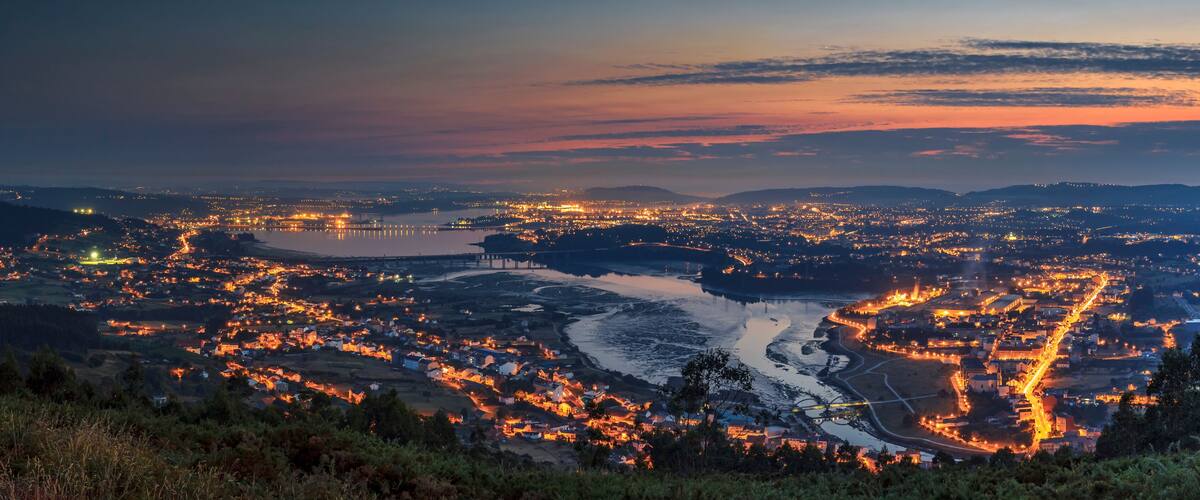 A cityscape at dusk with a river winding through it.