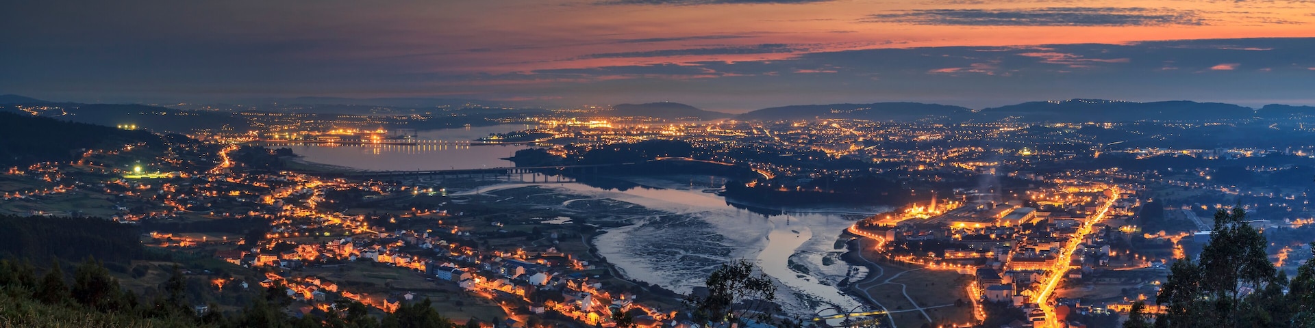 A cityscape at dusk with a river winding through it.