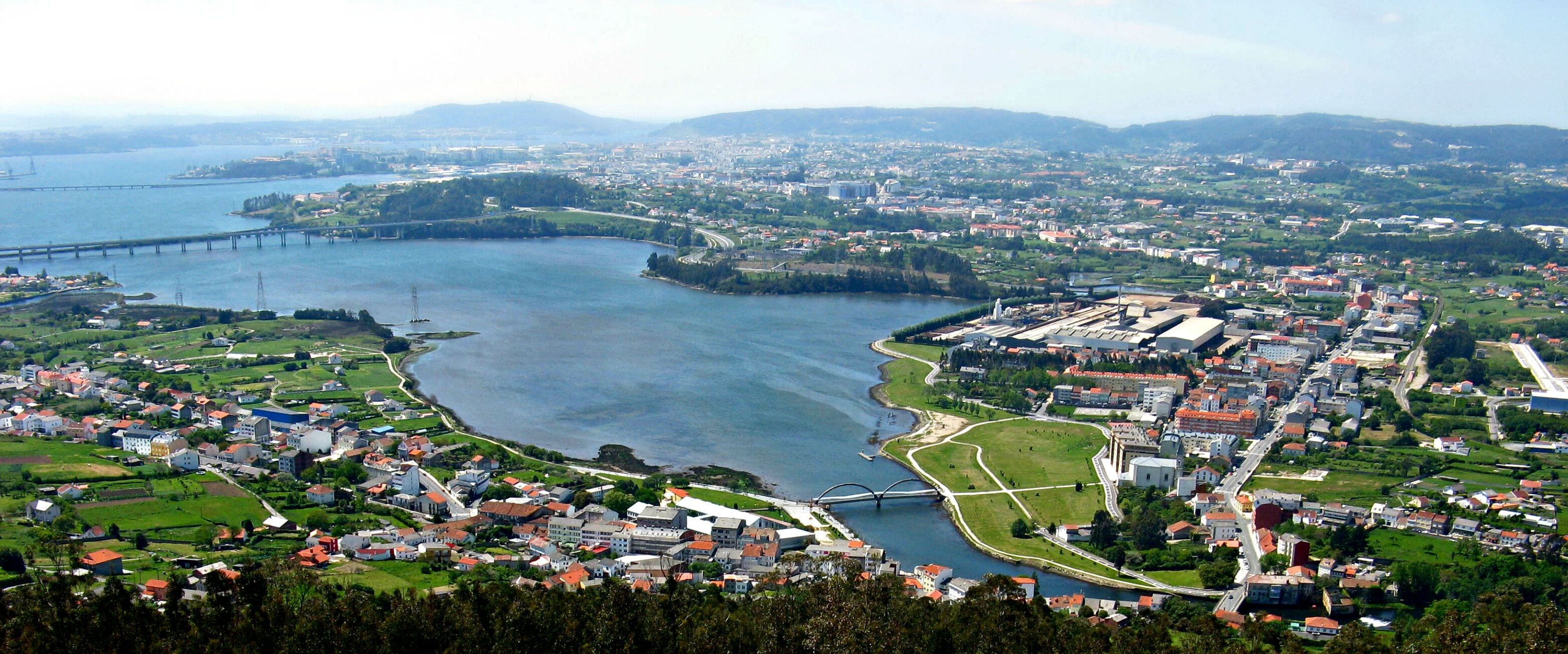 A coastal town with a river, a bridge, and a distant mountain range.