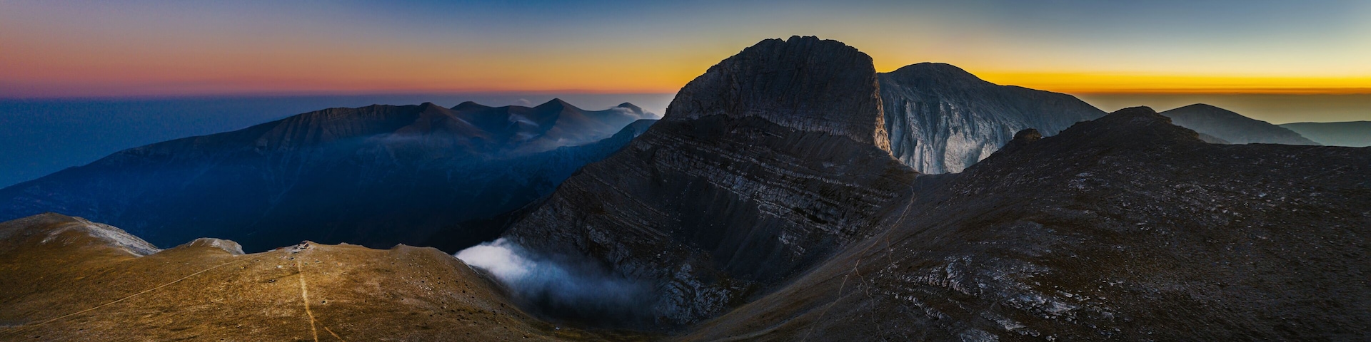 A mountain range with a prominent peak and a valley.