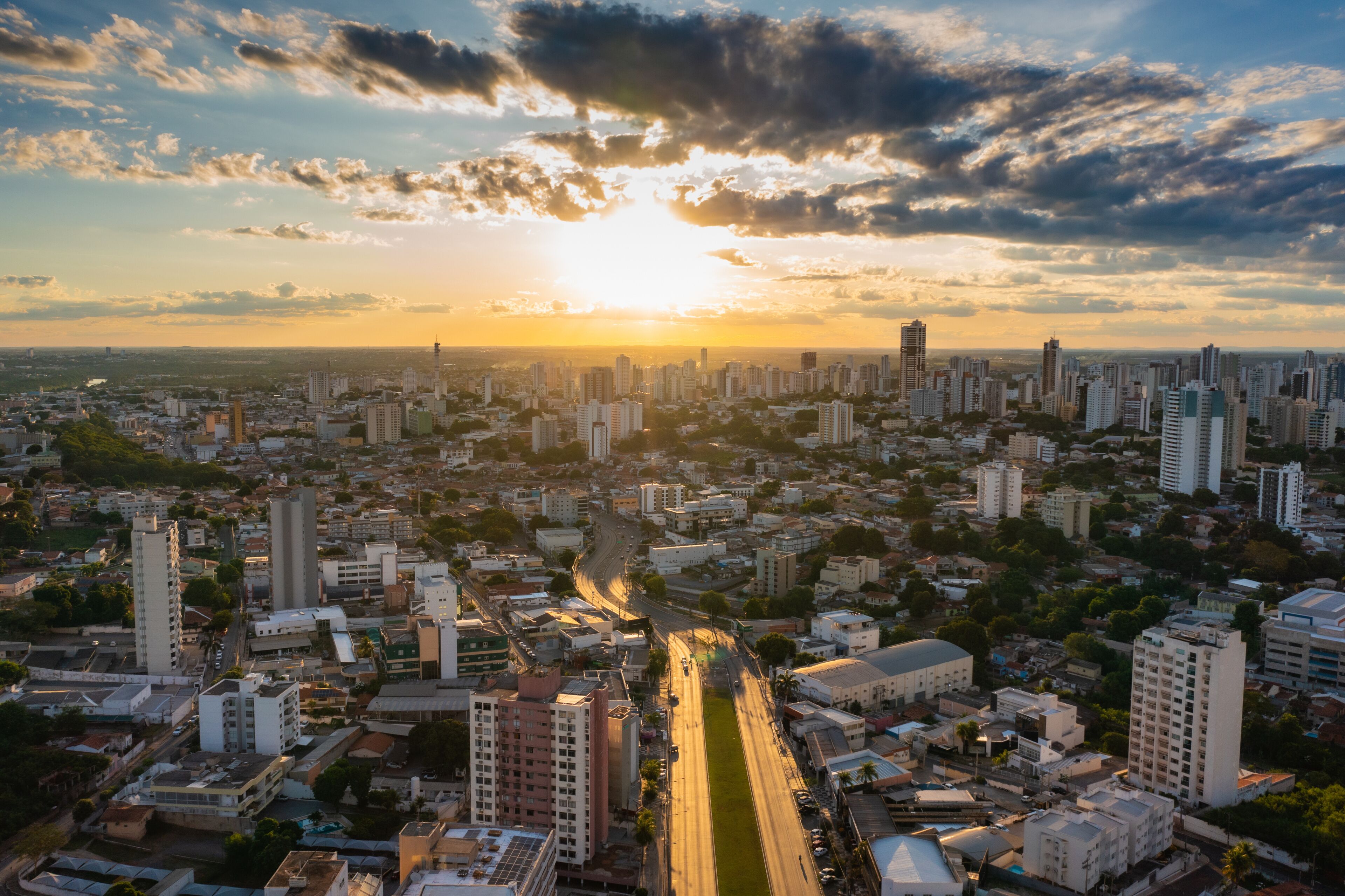 A cityscape with a river running through it, surrounded by high-rise buildings and a sunset in the background.