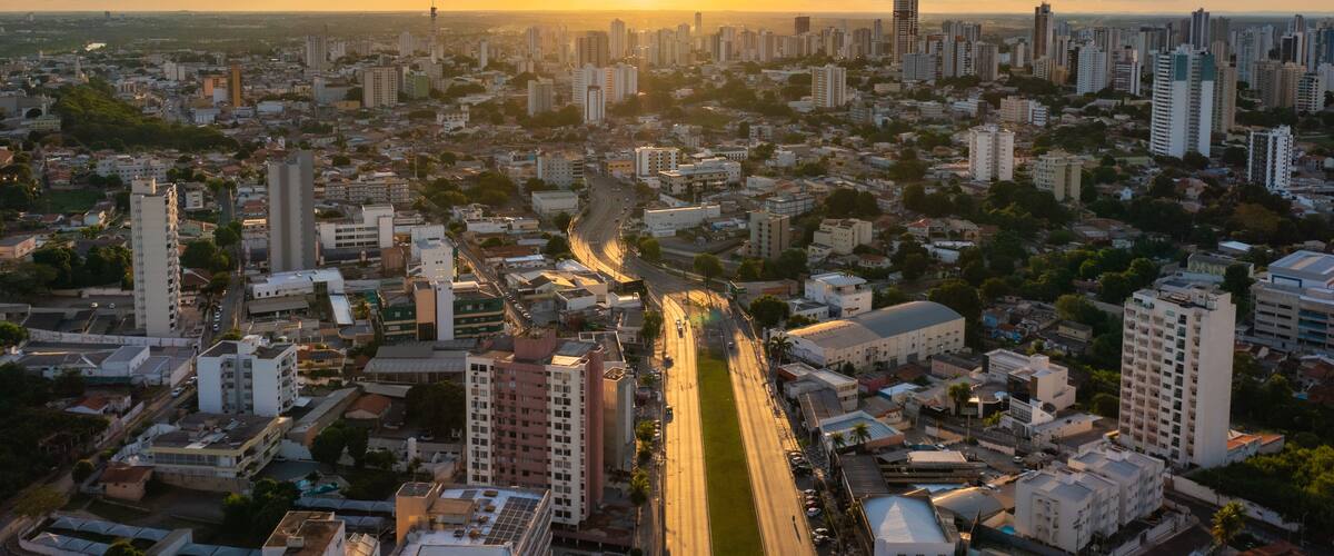 A cityscape with a river running through it, surrounded by high-rise buildings and a sunset in the background.