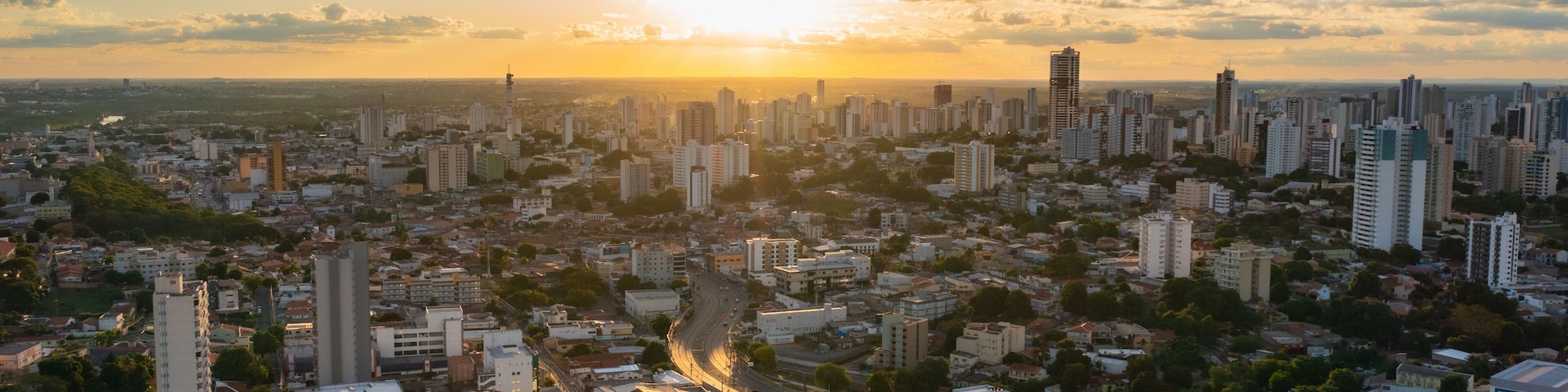 A cityscape with a river running through it, surrounded by high-rise buildings and a sunset in the background.