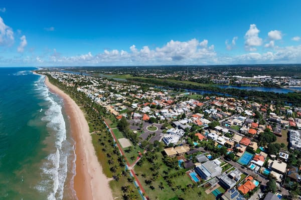 Uma vila costeira com praia, área residencial e um rio.
