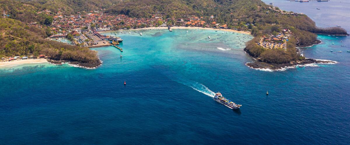 A coastal town with a marina, surrounded by mountains and clear blue waters.