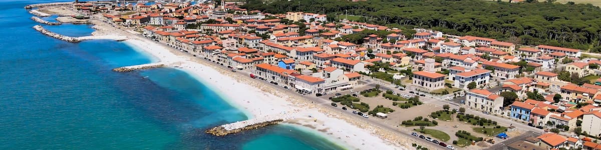 A coastal town with a beach, clear blue waters, and red-roofed buildings.