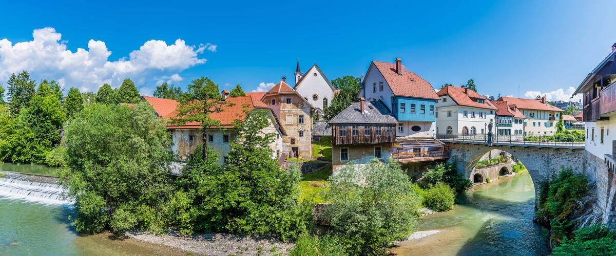 A river flowing through a town with historic buildings and a stone bridge.