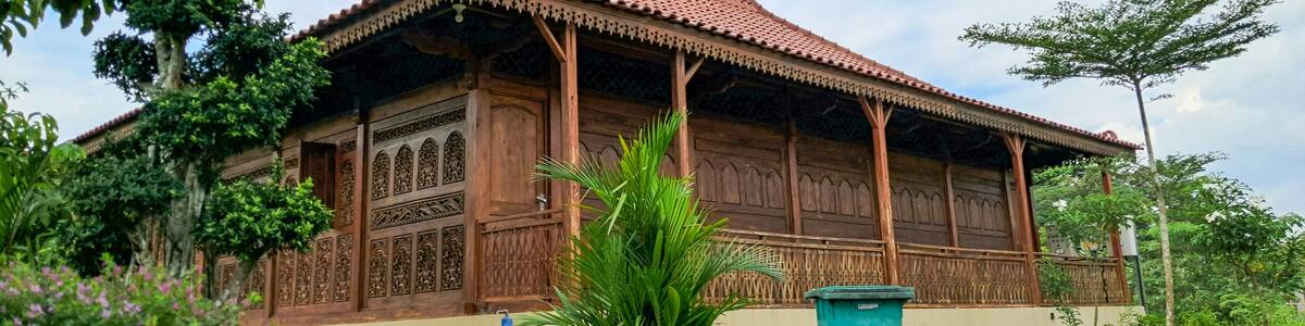 View of Rumah Joglo or Joglo house with a background of blue sky and trees in Mas Kemambang, Purwokerto. Joglo house is a traditional house typical of Central Java made of wood