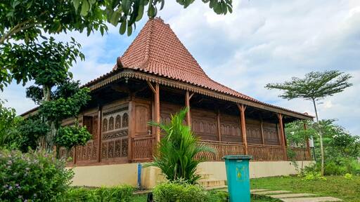 View of Rumah Joglo or Joglo house with a background of blue sky and trees in Mas Kemambang, Purwokerto. Joglo house is a traditional house typical of Central Java made of wood