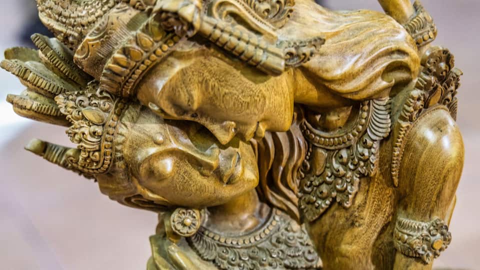 A detailed golden statue with intricate carvings and a figure in a dynamic pose.