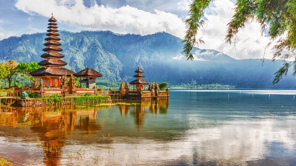 A serene lake with traditional pagodas and lush greenery in the background.