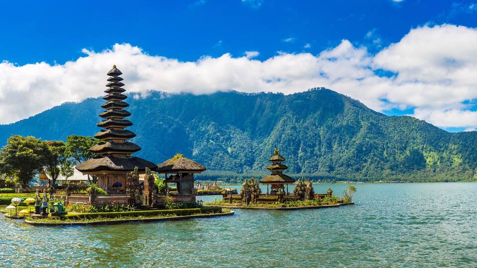 A serene lake with traditional Balinese temples and lush greenery.
