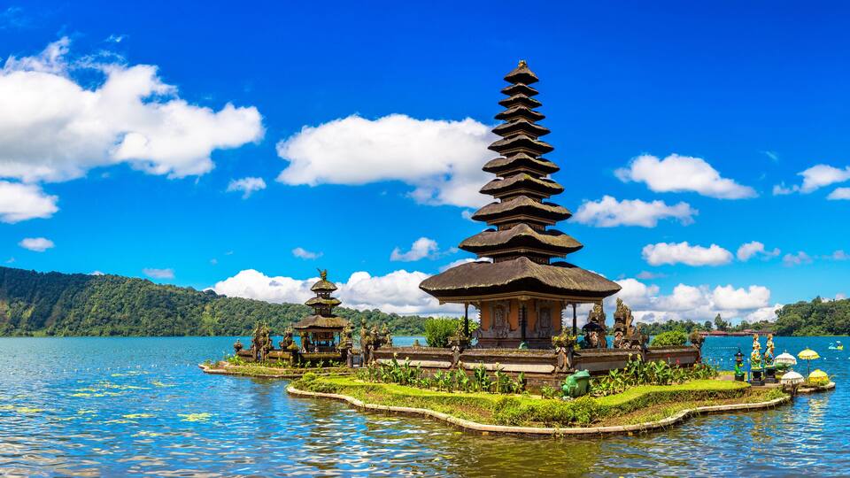 A traditional Balinese temple on a lake surrounded by lush greenery.
