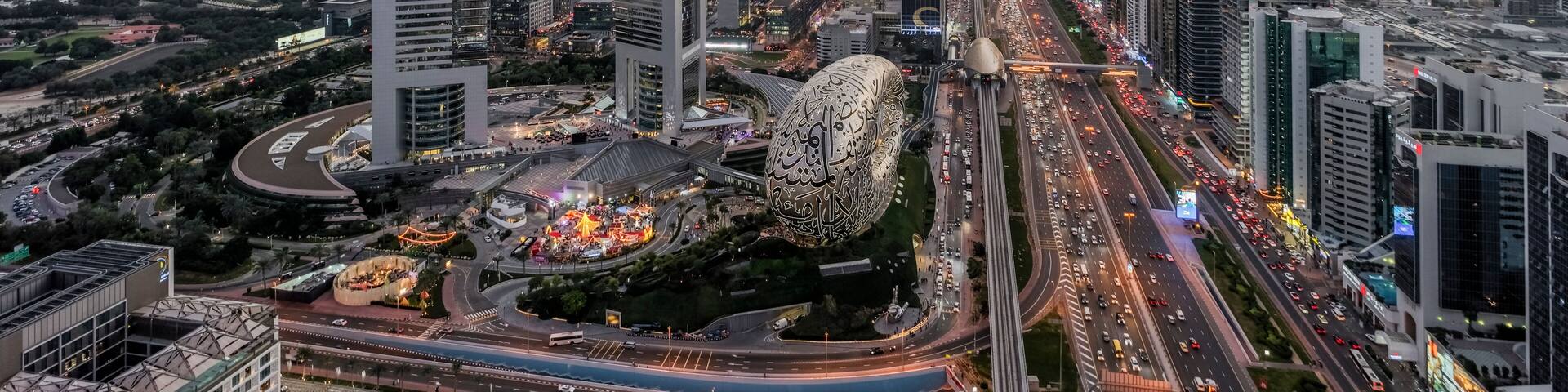 A cityscape with modern skyscrapers, a roundabout, and a prominent clock tower.