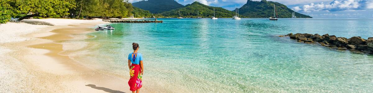 Travel tourist woman at French Polynesia beach on Huahine island cruise excursion on Tahiti holiday vacaton. Girl wearing polynesian sarong skirt banner panorama crop.